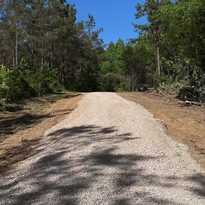 A new gravel drive running back through cleared woods.